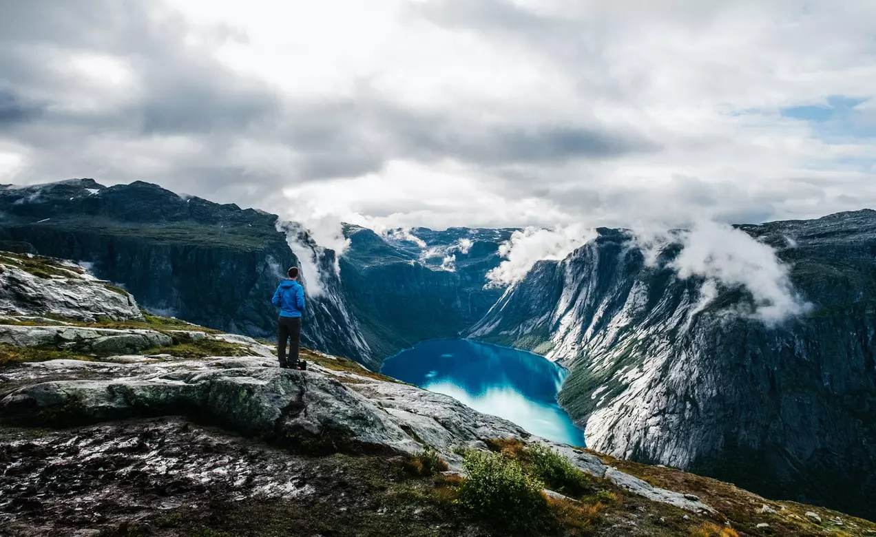 A man on a mountaintop has outdoor gear made with THERMOLITE® EcoMade technology, which is made from 100% recycled resources.