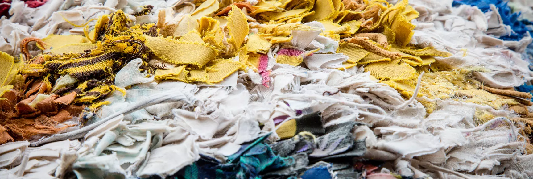 An image of textile scraps in a landfill shows how waste is a real apparel industry issue that requires innovative solutions.